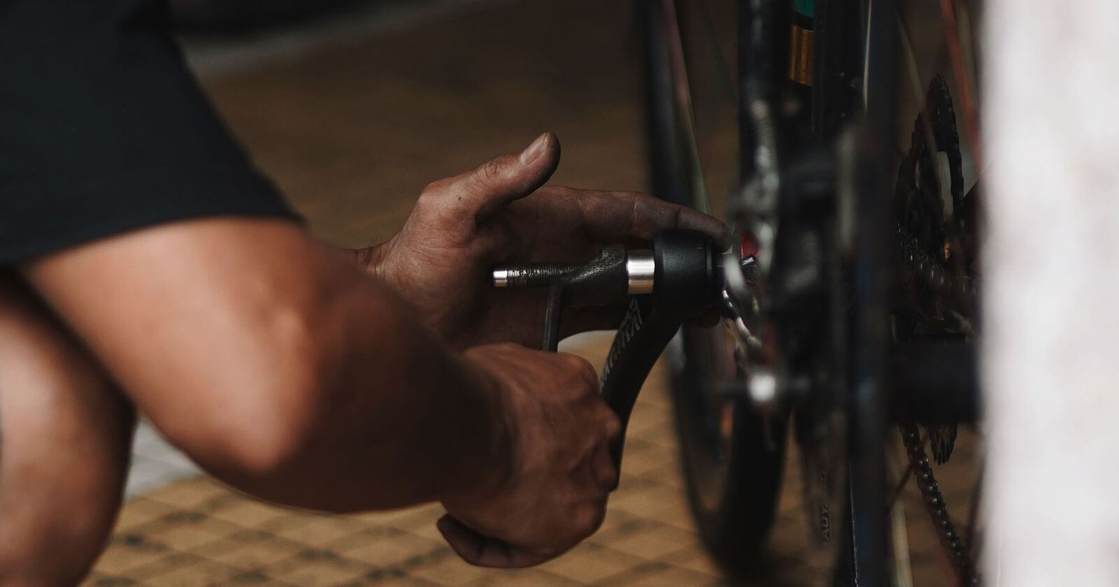 Hände mit Werkzeug an einem Fahrrad in der Werkstatt